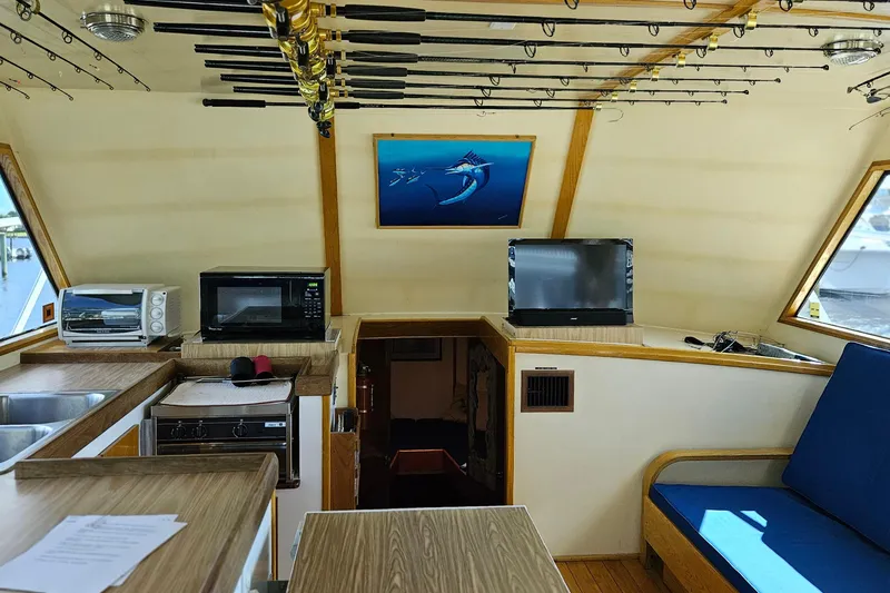 Slide: The Image of Interior of 1989 Breaux Brothers Sportfisherman with fishing rods, appliances, and seating area. - 19