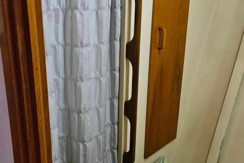 Slide: The Image of Interior of 1989 Breaux Brothers Sportfisherman, featuring wood paneling and a white curtain. - 21