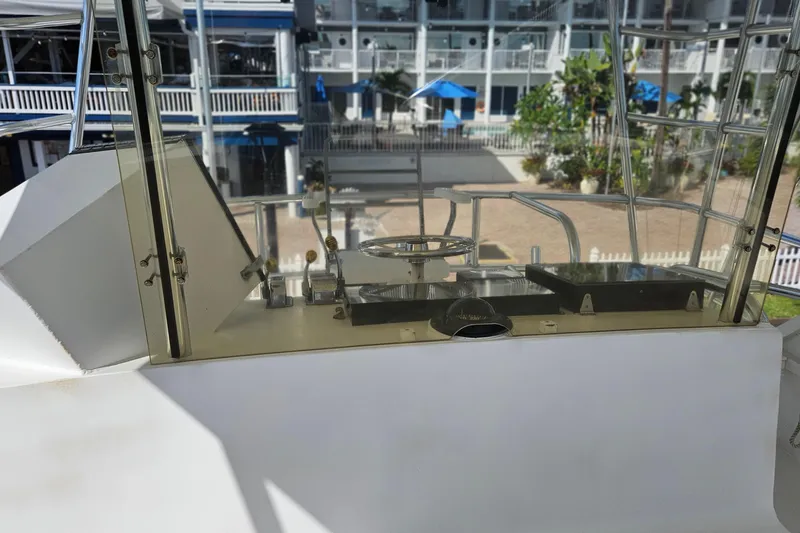Slide: The Image of 1989 Breaux Brothers Sportfisherman helm with steering wheel and controls, docked near a marina. - 29
