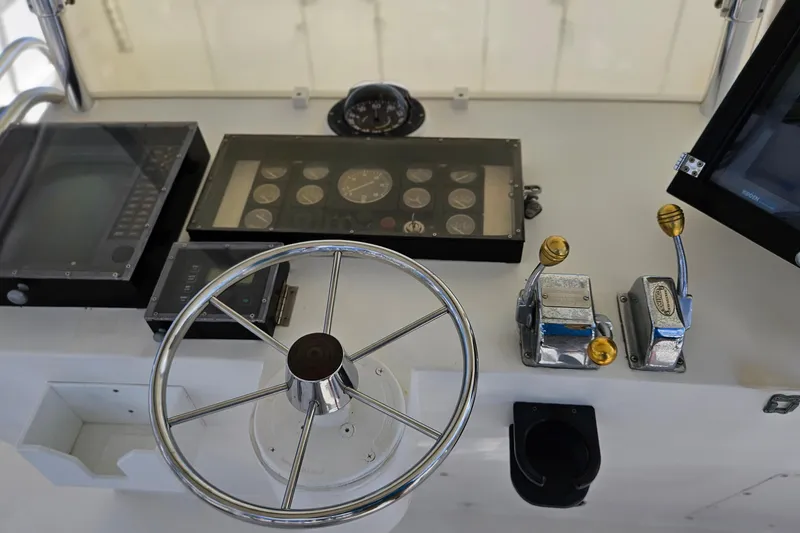 Slide: The Image of Control panel of a 1989 Breaux Brothers Sportfisherman boat with steering wheel and gauges. - 30