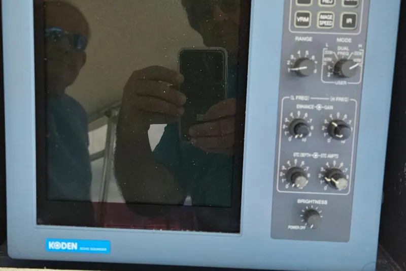 Slide: The Image of Koden marine equipment on 1989 Breaux Brothers Sportfisherman, with reflection of two people. - 32