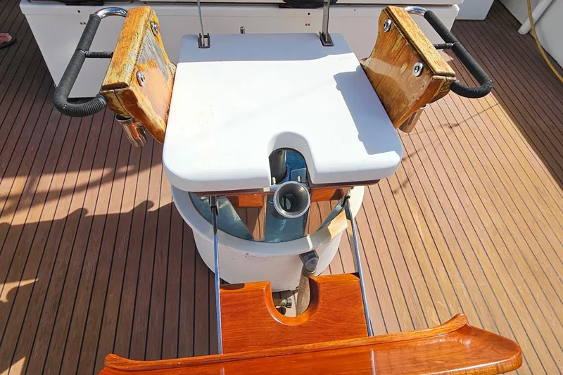 Slide: The Image of 1989 Breaux Brothers Sportfisherman fishing chair on teak deck, featuring wooden armrests and rod holder. - 41