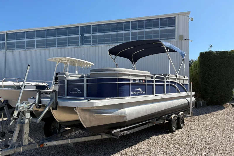 Slide: The Image of 2021 Bennington 24 SVRC pontoon boat on trailer, parked outdoors near a building. - 20