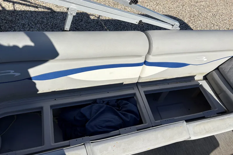 Slide: The Image of 2021 Bennington 24 SVRC pontoon boat interior with gray seating, parked in a marina. - 5