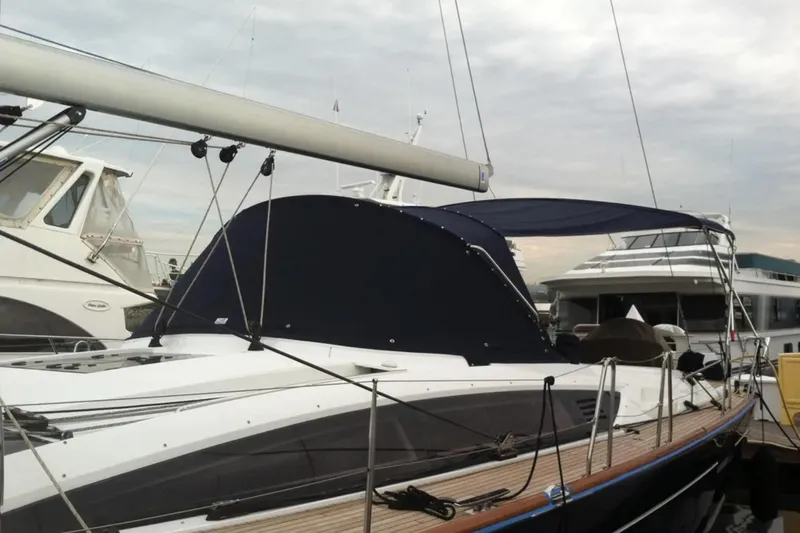 Slide: The Image of 2011 Jeanneau 57 sailboat docked, featuring sleek design and dark canopy. - 6