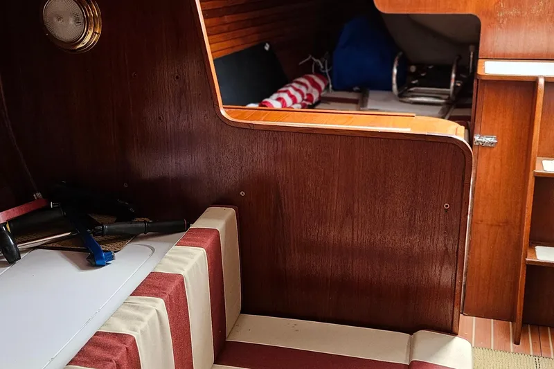 Slide: The Image of Interior of 1977 Peterson 34 Sloop, featuring wood paneling and striped seating. - 16