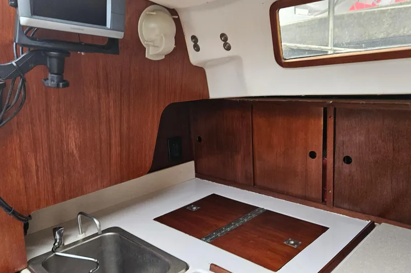 Slide: The Image of Interior of 1977 Peterson 34 Sloop with wooden cabinetry and compact kitchen area. - 23