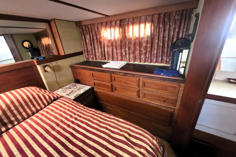 Slide: The Image of Interior of 1979 Trojan 44 Motor Yacht with striped bedding and wooden cabinetry. - 15