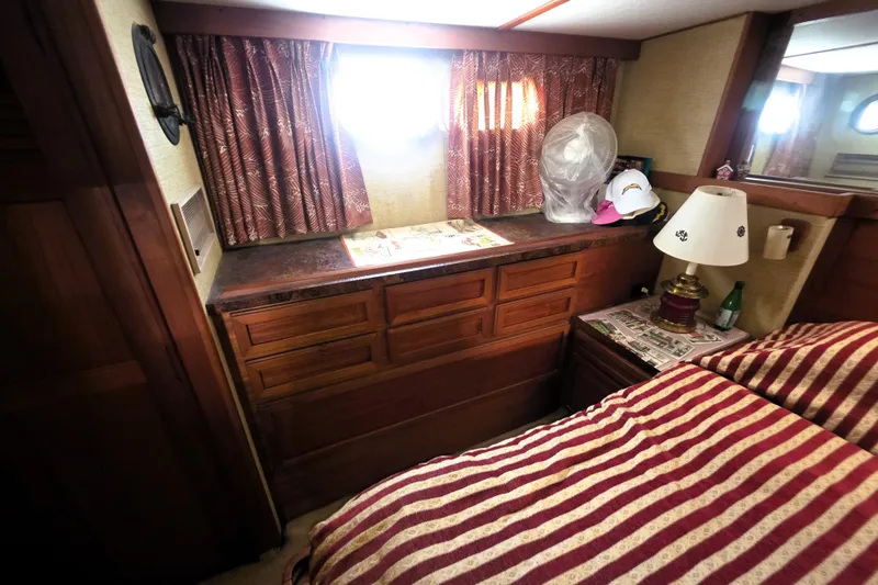 Slide: The Image of 1979 Trojan 44 Motor Yacht interior with striped bedding, wooden cabinetry, and decorative lamp. - 16