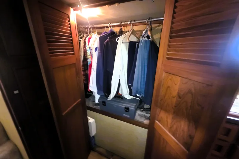 Slide: The Image of Closet interior on 1979 Trojan 44 Motor Yacht with hanging clothes and wooden doors. - 24