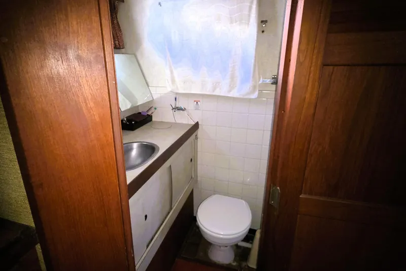 Slide: The Image of 1979 Trojan 44 Motor Yacht bathroom with sink, toilet, and wooden cabinetry. - 25