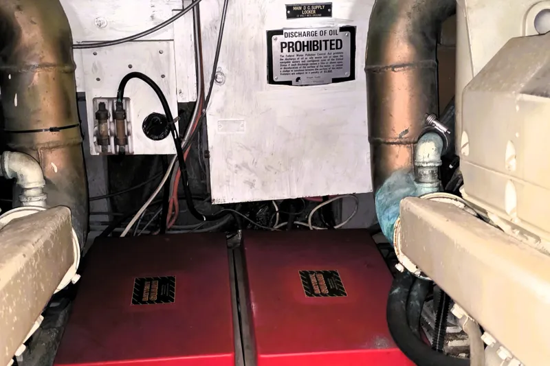 Slide: The Image of Engine room of a 1979 Trojan 44 Motor Yacht with visible components and warning sign. - 29