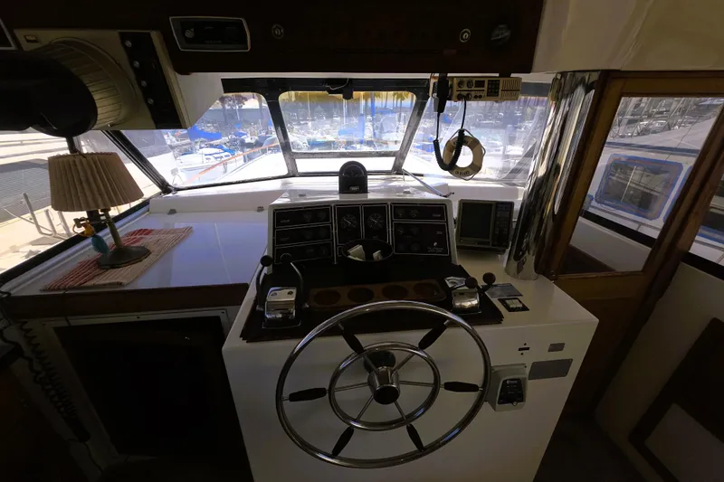 Slide: The Image of 1979 Trojan 44 Motor Yacht helm with steering wheel, gauges, and marina view. - 4