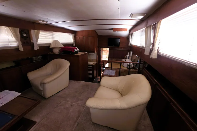 Slide: The Image of 1979 Trojan 44 Motor Yacht interior with cozy seating, wood paneling, and natural light. - 7