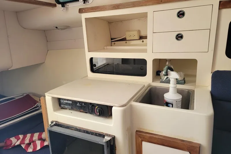 Slide: The Image of Interior of 1997 Albin 28 Tournament Express with kitchenette, sink, and storage compartments. - 10