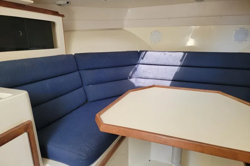 Slide: The Image of Interior of 1997 Albin 28 Tournament Express with blue cushioned seating and wooden table. - 7