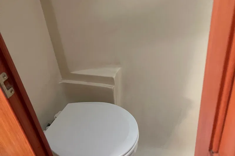 Slide: The Image of Compact bathroom in a 2008 Hunter 49 yacht, featuring a white toilet and wooden door. - 41