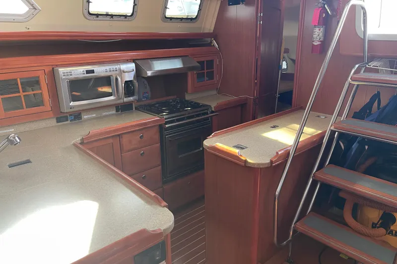 Slide: The Image of Interior of 2008 Hunter 49 yacht kitchen with stove, microwave, and wooden cabinetry. - 56