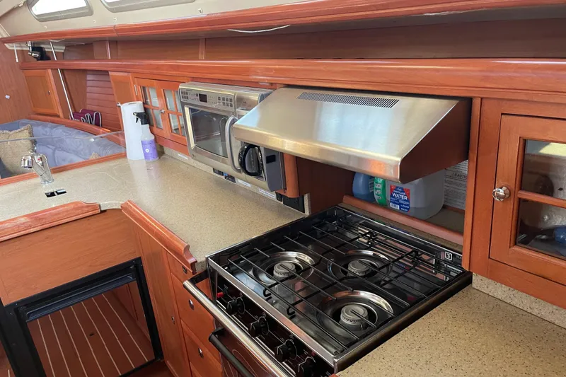 Slide: The Image of Galley kitchen in 2008 Hunter 49 yacht with stove, microwave, and wooden cabinetry. - 59