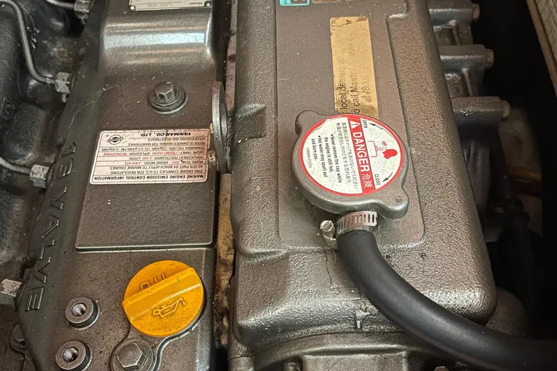 Slide: The Image of Engine components of a 2008 Hunter 49, featuring warning labels and a yellow oil cap. - 7