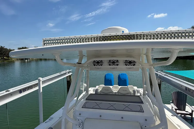Slide: The Image of 2005 Marlago 35 boat docked on a serene lake under a clear blue sky. - 24
