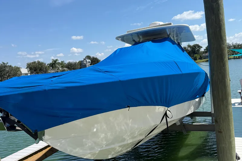 Slide: The Image of 2005 Marlago 35 boat covered with blue tarp on a docked lift. - 26