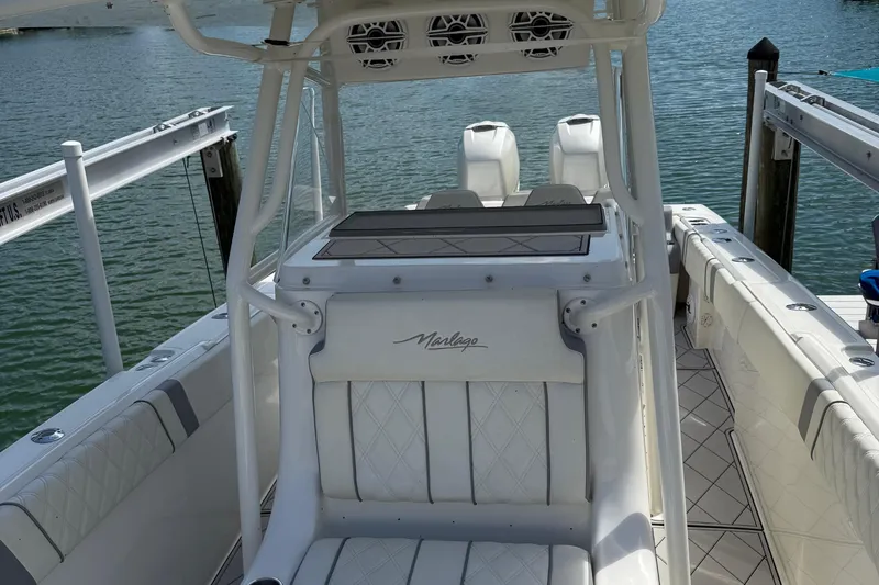 Slide: The Image of 2005 Marlago 35 boat interior with white seating and dual engines, docked by the water. - 38