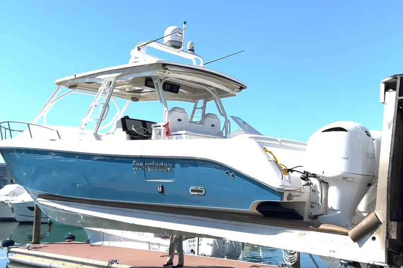 Slide: The Image of 2017 Everglades 360LXC boat on lift, blue and white design, docked at marina. - 14