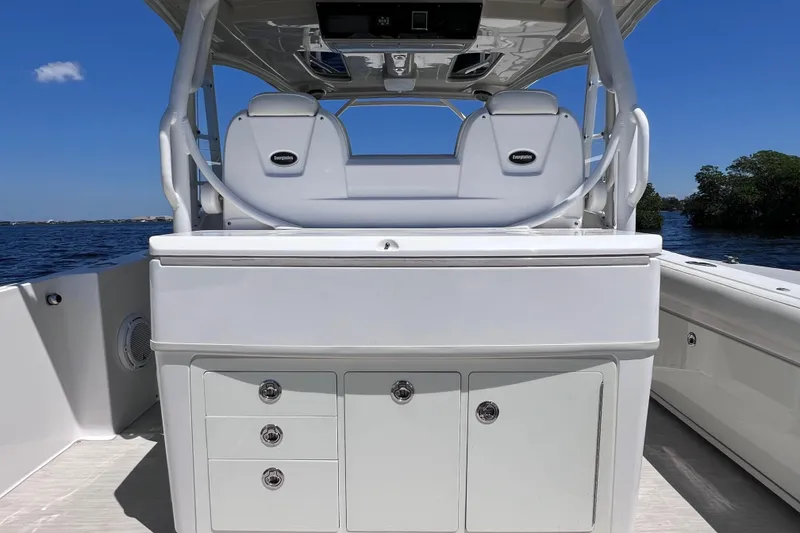 Slide: The Image of 2017 Everglades 360LXC boat interior with seating and storage, on a sunny day. - 24