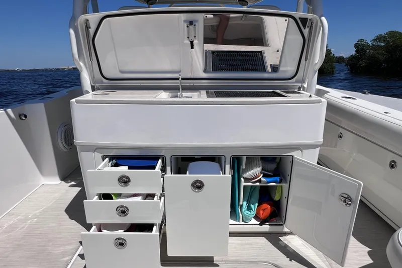 Slide: The Image of 2017 Everglades 360LXC boat with open storage compartments and sink, docked on water. - 25
