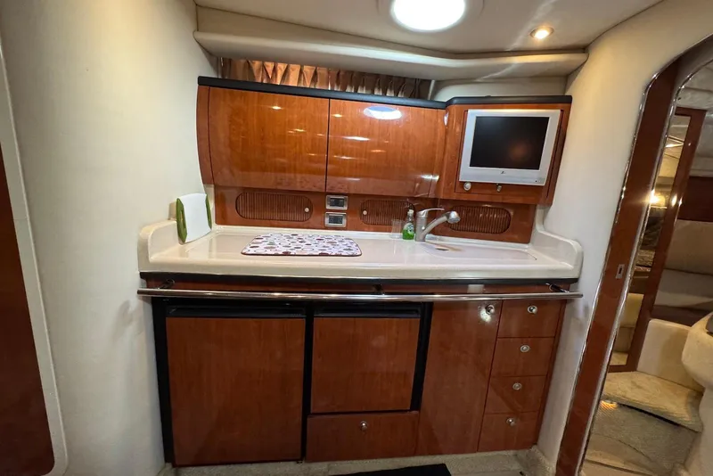 Slide: The Image of 2004 Sea Ray 360 Sundancer yacht kitchen with wood cabinets, sink, and small TV. - 22