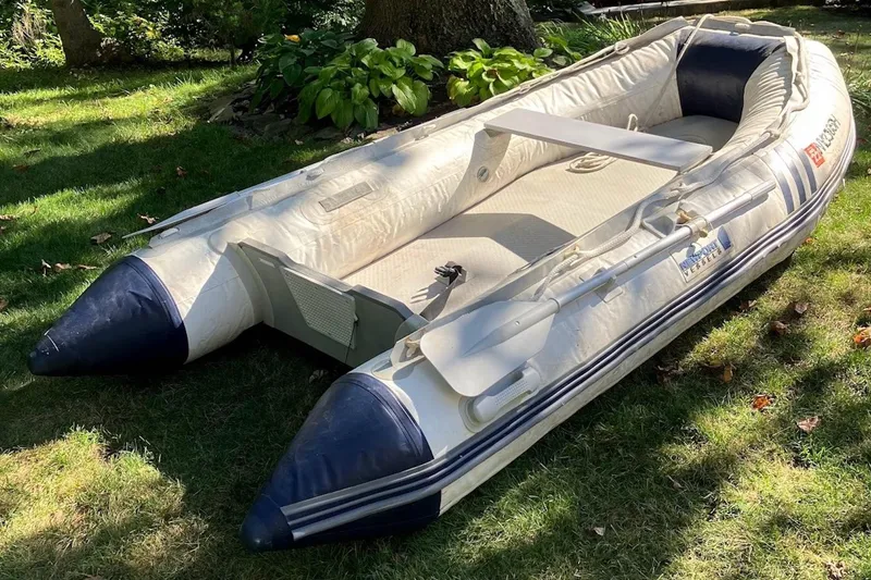 Slide: The Image of Inflatable boat on grass, featuring blue and white design, with oars attached. - 33