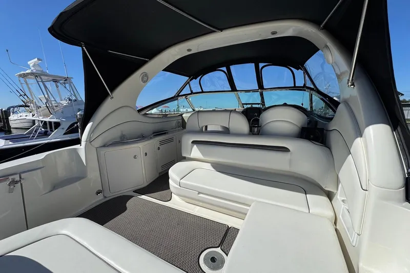 Slide: The Image of 2004 Sea Ray 360 Sundancer interior with white seating and helm, docked at marina. - 5