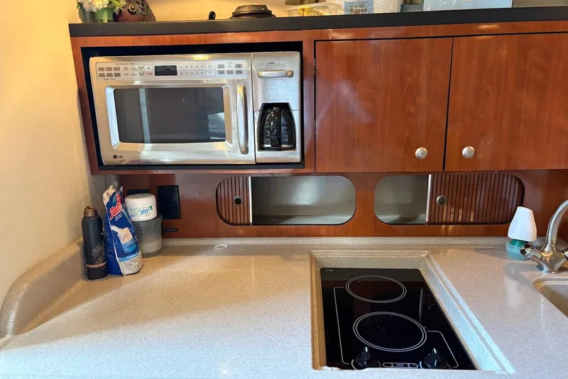 Slide: The Image of 2007 Sea Ray 340 Sundancer galley with microwave, stove, and wooden cabinetry. - 11