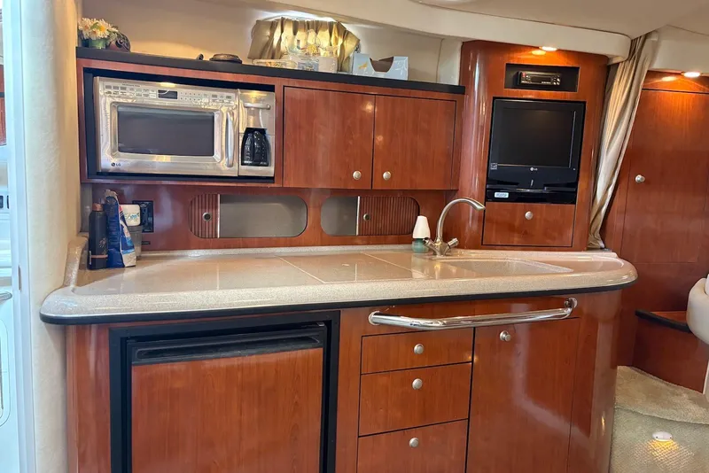 Slide: The Image of 2007 Sea Ray 340 Sundancer interior kitchen with wood cabinetry, microwave, and sink. - 12