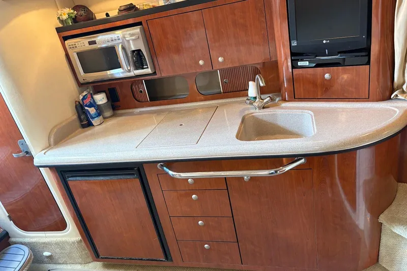Slide: The Image of 2007 Sea Ray 340 Sundancer galley with sink, microwave, and wooden cabinetry. - 26