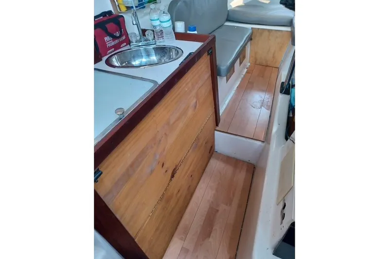 Slide: The Image of Interior of a 1996 McGregor 26 boat with wooden flooring and compact kitchenette. - 10