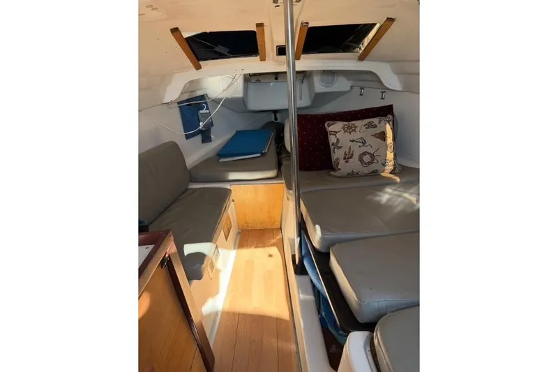 Slide: The Image of Interior of a 1996 McGregor 26 sailboat with cushioned seating and wooden accents. - 11