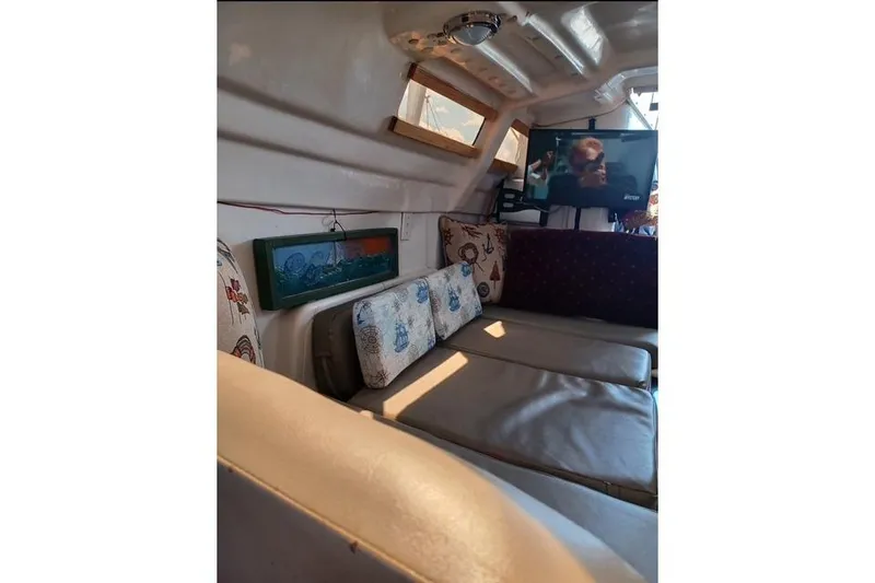 Slide: The Image of Interior of a 1996 McGregor 26 boat with cozy seating and a mounted TV. - 12