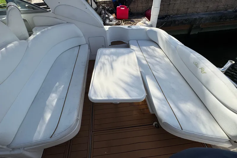 Slide: The Image of 1999 Searay 340 Sundancer boat interior with white seating and table on wooden deck. - 3