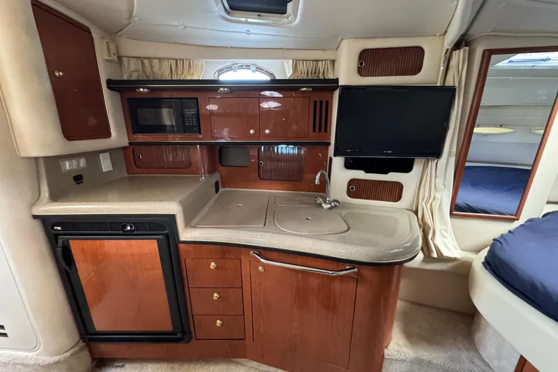 Slide: The Image of 1999 Searay 340 Sundancer interior with kitchenette, microwave, sink, and TV. - 9