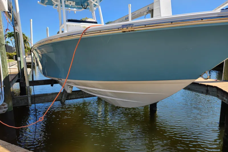 Slide: The Image of 2018 Sportsman Masters 247 Bay Boat on lift, blue hull, docked by water. - 17