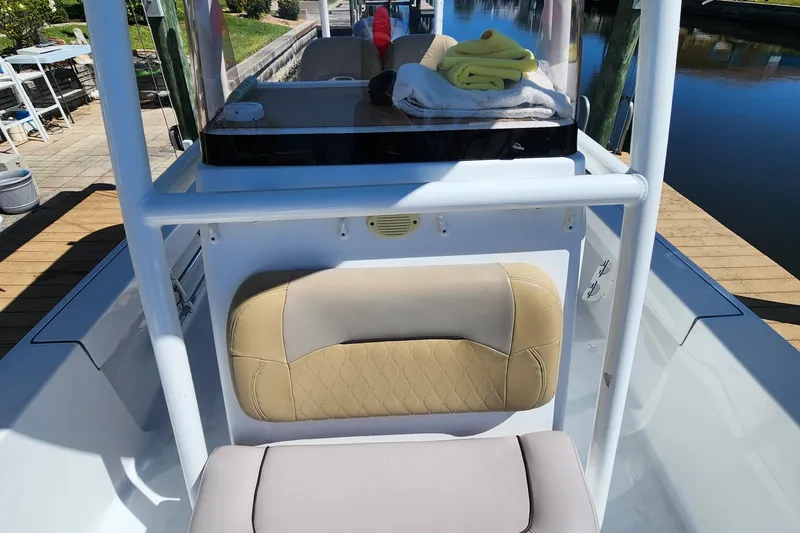 Slide: The Image of 2018 Sportsman Masters 247 Bay Boat interior with beige seating and console, docked by calm water. - 6