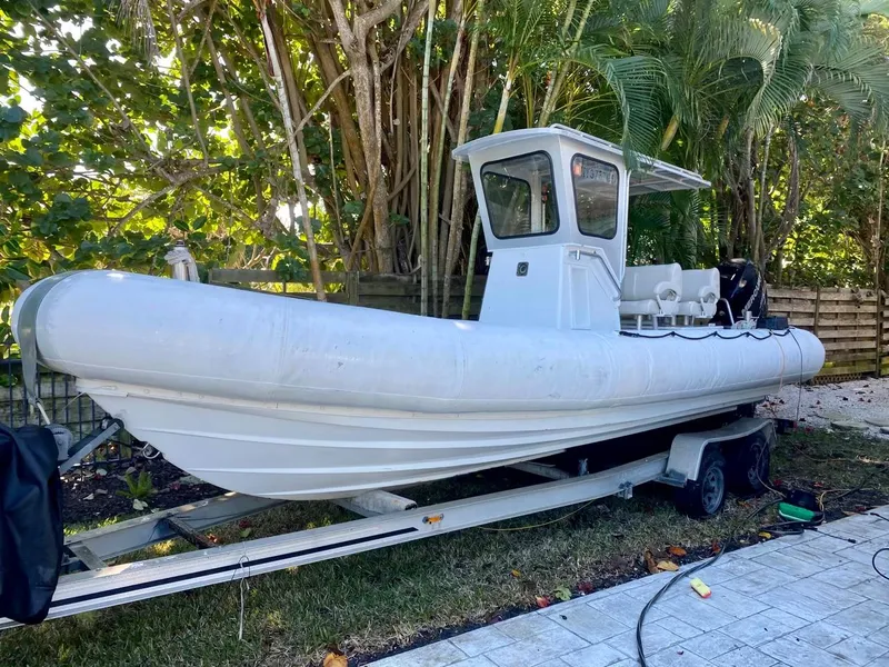 Slide: The Image of White 2001 Willard 25 boat on a trailer, surrounded by lush greenery. - 1