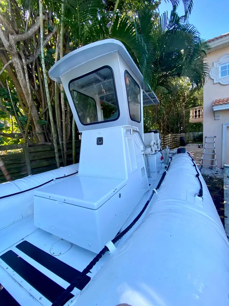 Slide: The Image of White 2001 Willard 25 boat with cabin, docked near tropical foliage and house. - 7