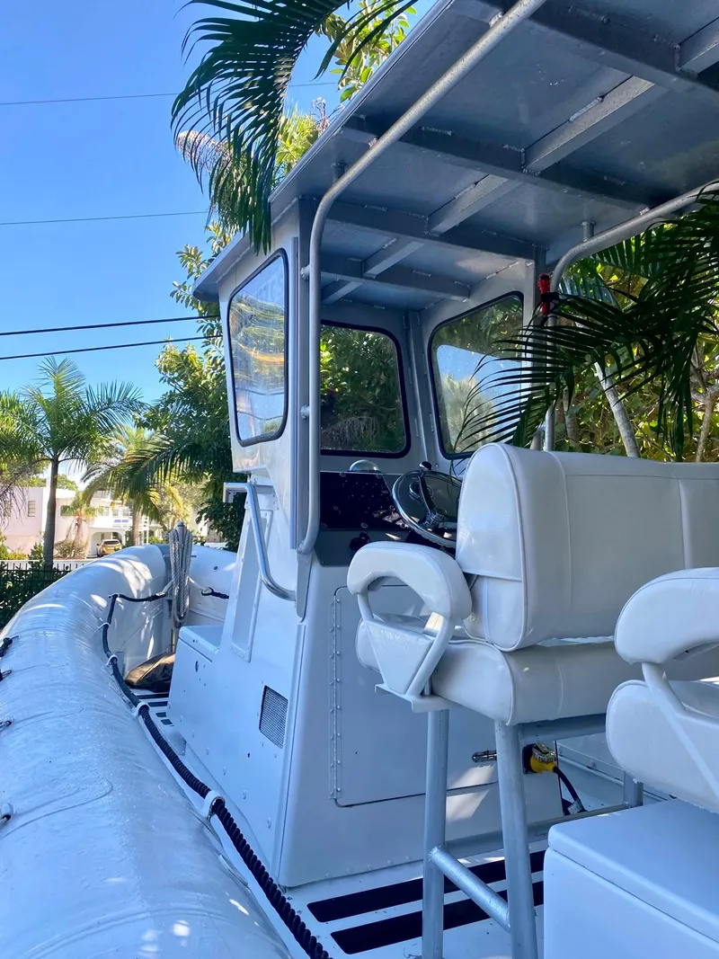 Slide: The Image of 2001 Willard 25 boat with white seating and canopy, surrounded by palm trees. - 8