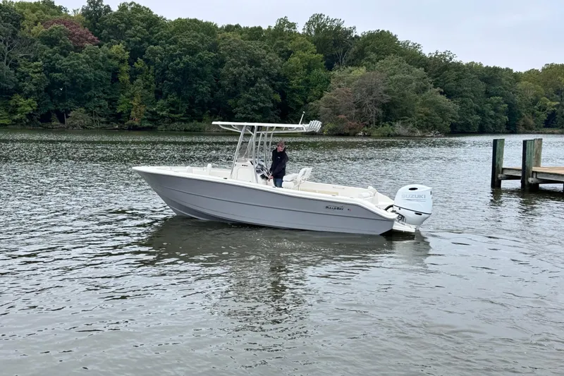 Slide: The Image of 2026 Bulls Bay 230 Center Console boat on a calm lake near a wooded shoreline. - 5