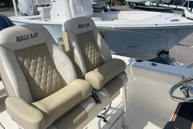 Slide: The Image of 2026 Bulls Bay 255CC boat with beige cushioned seats and steering wheel. - 3
