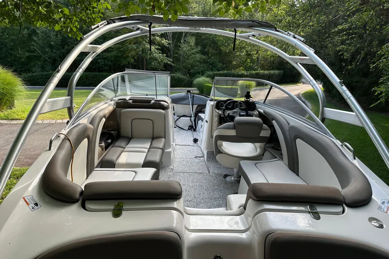 Slide: The Image of 2012 Yamaha Boats 242 Limited S interior with seating and steering, surrounded by greenery. - 1