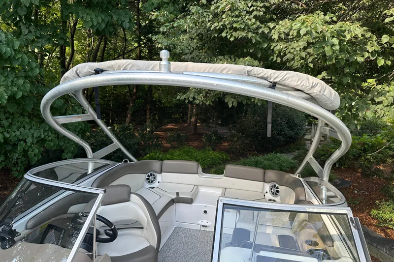 Slide: The Image of 2012 Yamaha Boats 242 Limited S interior with canopy, surrounded by lush greenery. - 13